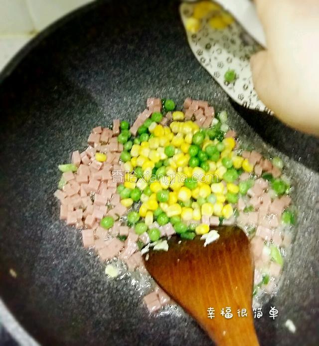 接着放入玉米粒和青豆粒翻炒。