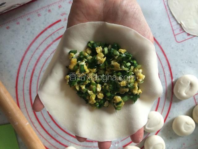拿一个面皮放在掌心，乘一勺韭菜鸡蛋馅放在面皮一边