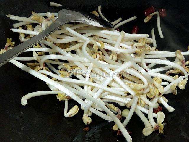 陆续放入花生芽翻炒片刻，用适量的开水从锅边淋下去炒至花生芽软塌。