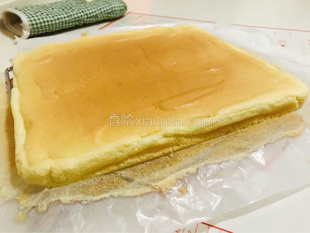 提着油纸边缘把蛋糕从烤盘中提出放到案板上。慢慢剥离边缘的纸。