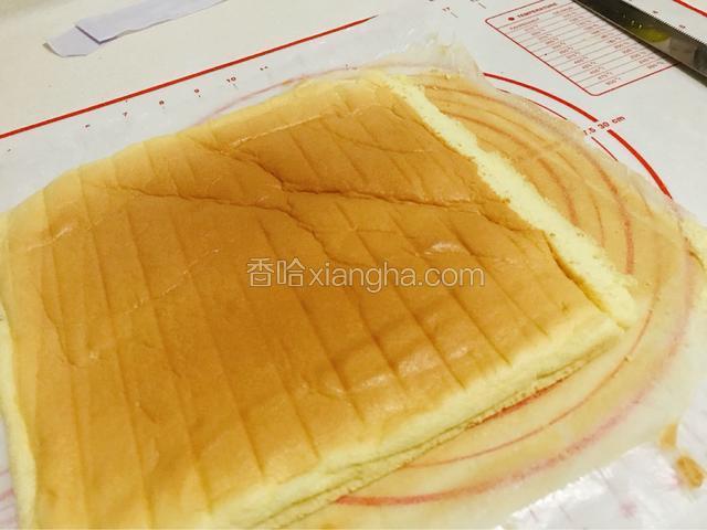 油纸不要扔，铺在台面上。再把蛋糕翻面扣在上面。用锯齿刀在蛋糕的短边切掉一角。