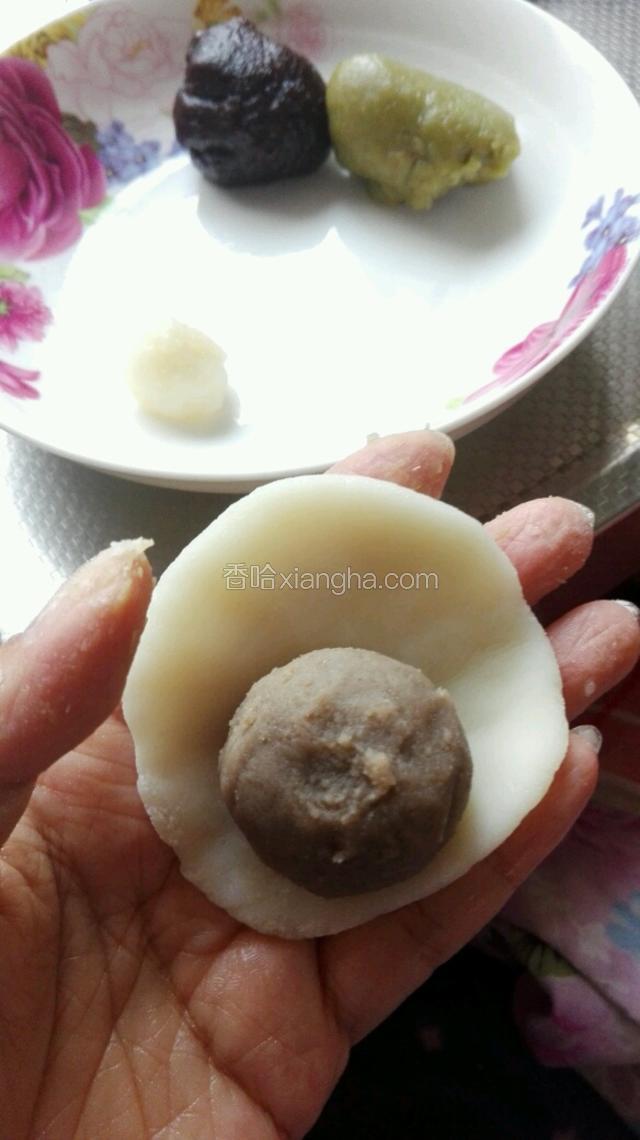 取一个冰皮剂子，用手压成小圆饼，中间放上油栗绿豆沙馅。