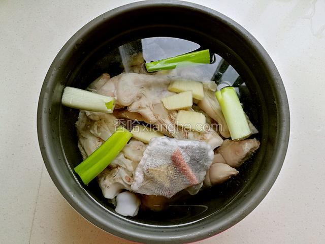把猪蹄扔进压力锅，加水漫过猪蹄，放入葱段和切好的姜片，并加入香料包。