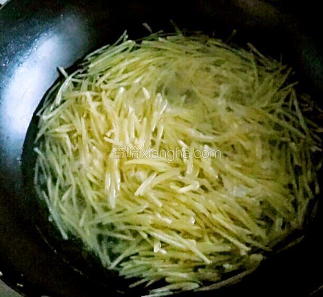 将土豆丝捞入锅中焯一下。