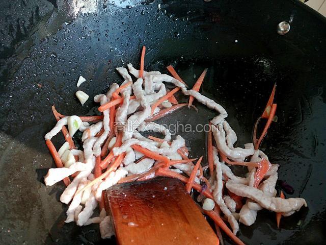 锅中加油，滑炒肉丝至熟。加蒜片爆香，加胡萝卜丝翻炒几下。
