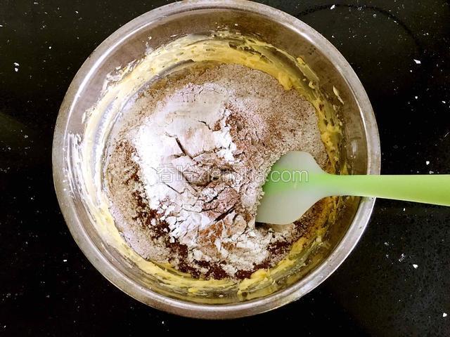 将混合粉筛入黄油蛋液中，用橡皮刀翻拌均匀至无干粉。