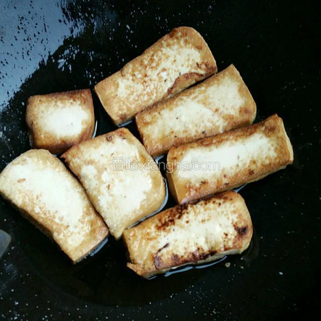炒锅中加油，油热后放入豆腐片，熬至两面金黄，盛出待用。