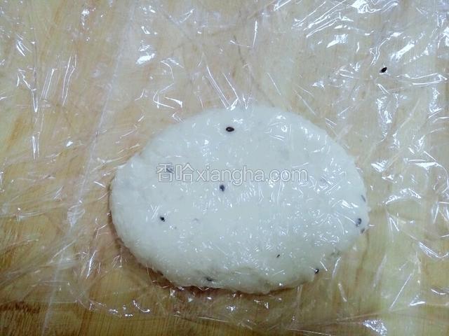 取一段保鲜膜，一半铺在案板上，放上面团，然后盖上另一半保鲜膜。