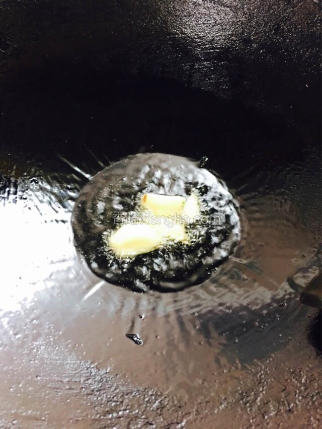 热锅冷油烧至五成热，放入蒜瓣爆香