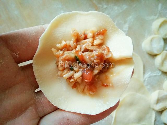 取一个面皮，放上饺子馅。