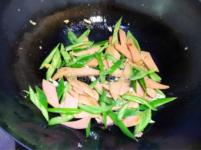 倒入青椒和火腿肠翻炒两分钟。