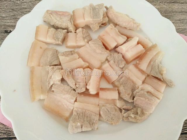 煮好的肉捞出晾凉，切成五花肉片，放入盘中备用。
