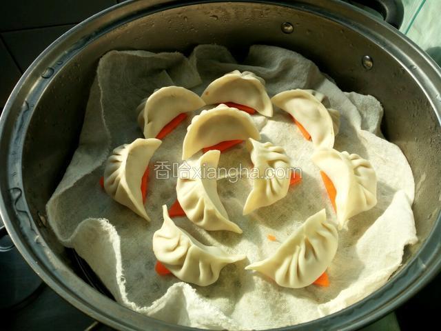 蒸锅上垫一层蒸笼布，再一片红萝卜放粘连，再放上饺子，冷水上锅，中火蒸10分钟即可。