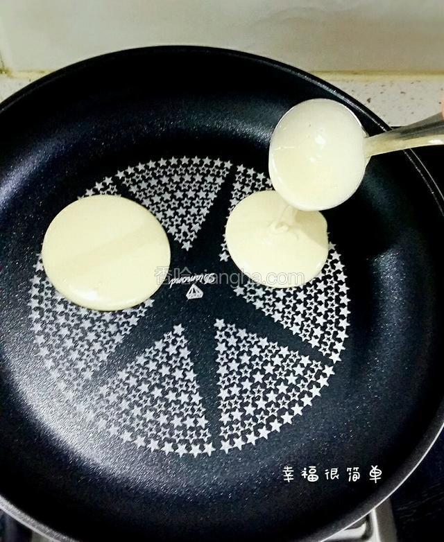 不粘锅里不道路任何油份，用勺子舀一勺面糊，开始烤饼。勺子高高抬起时，让面糊自然滑落，就能做出圆圆的松饼。