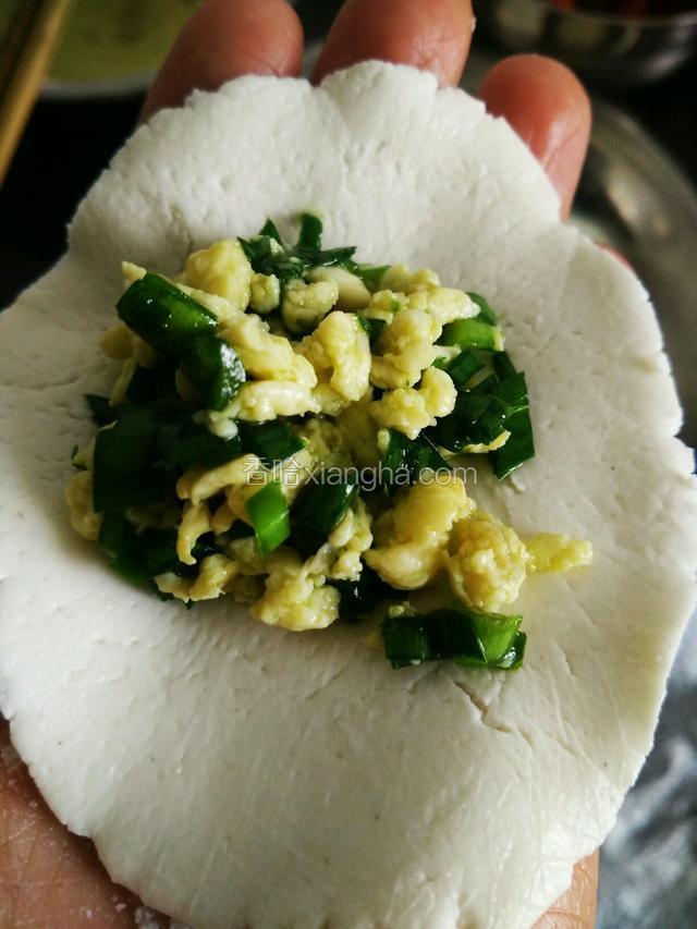 面团取小块压成薄饼状，放一勺韭菜鸡蛋馅包好
