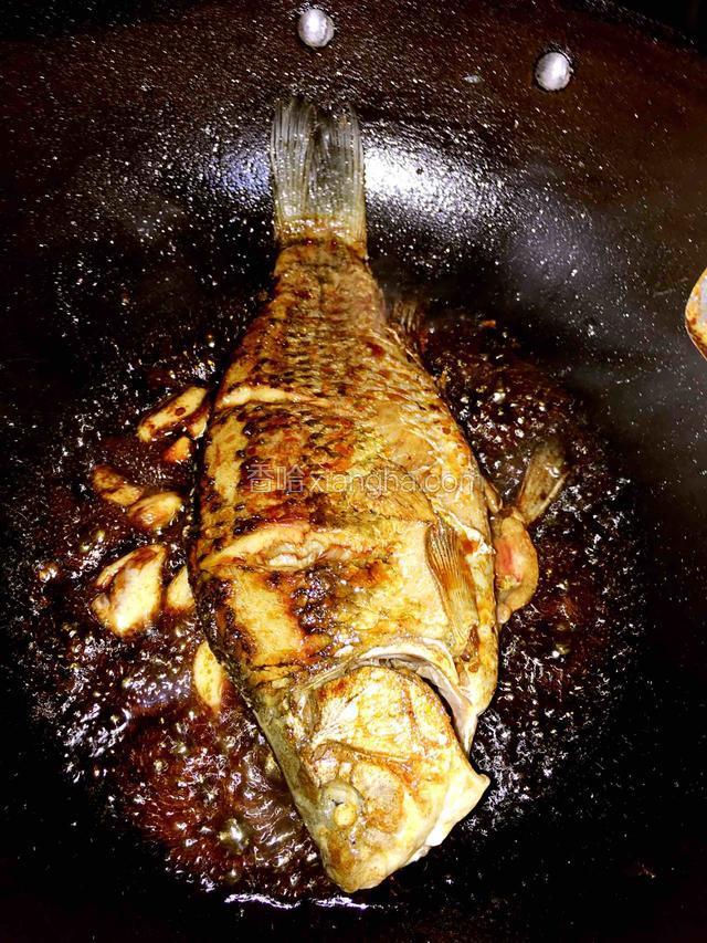 转中小火放入生姜蒜、料酒、生抽、老抽、糖醋慢慢烧制鱼上色