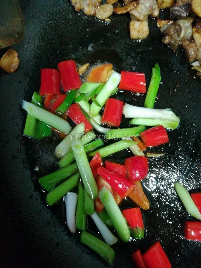 将炒好的鸡肉盛出或扒在一边，下辣椒和蒜杆，加盐炒半分钟。