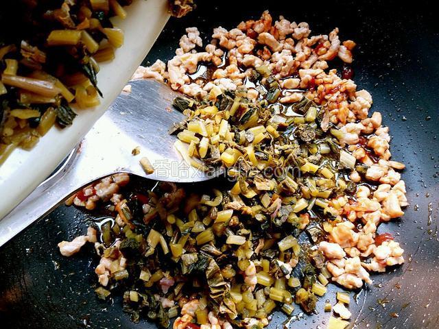 黄豆酱炒出香味后，把切好的腌菜倒入锅内炒制一分钟左右