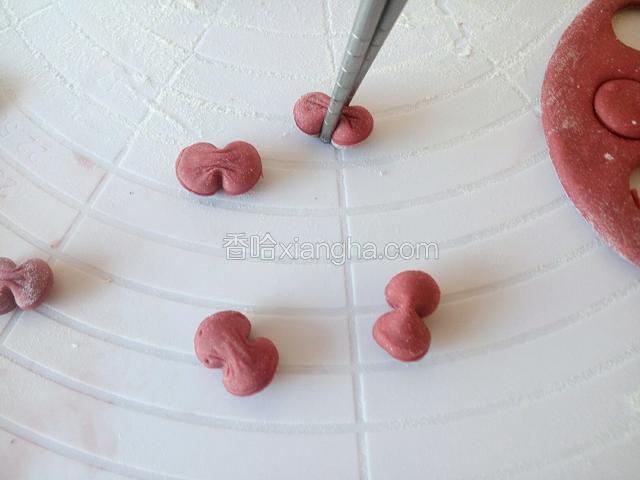 将红色小面饼用筷子从中间夹一下，成为蝴蝶结用于小鸡馒头头部装饰。