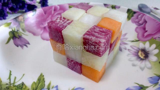 用切好的四种颜色的萝卜方块一个个堆好，搭建成一个魔方的造型，摆在盘子中。如图：