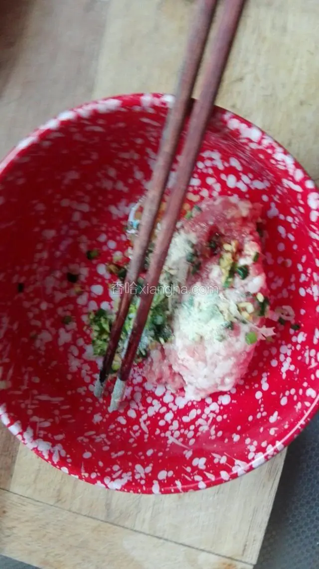 向猪前腿肉馅中加入葱末和姜末，生抽、香油、盐、白糖、胡椒粉，用筷子顺时针搅拌上劲。