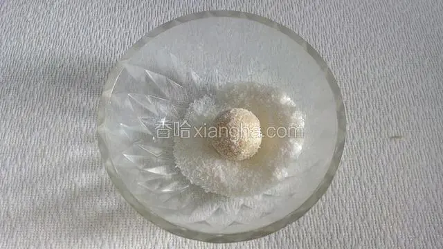 将它放入盛有剩余椰蓉的碗中滚一滚，让面球沾满椰蓉。一个椰蓉球胚子做好了。