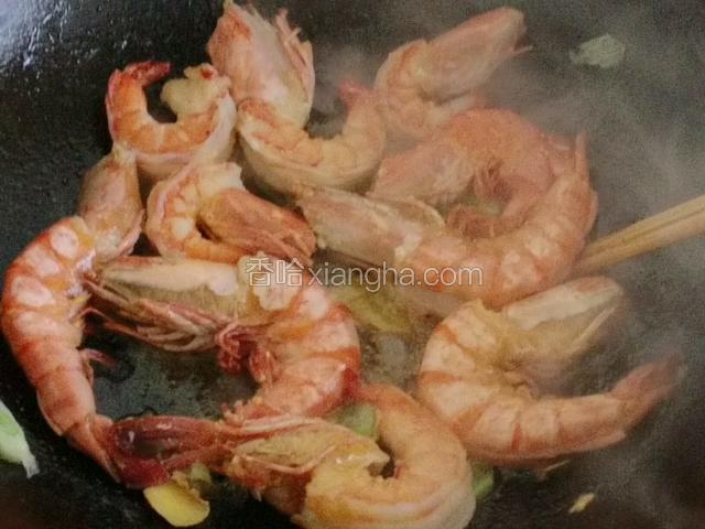 一面变红后，再翻至另一面！将腌制大虾滴料酒、葱姜汁倒入大虾中；
