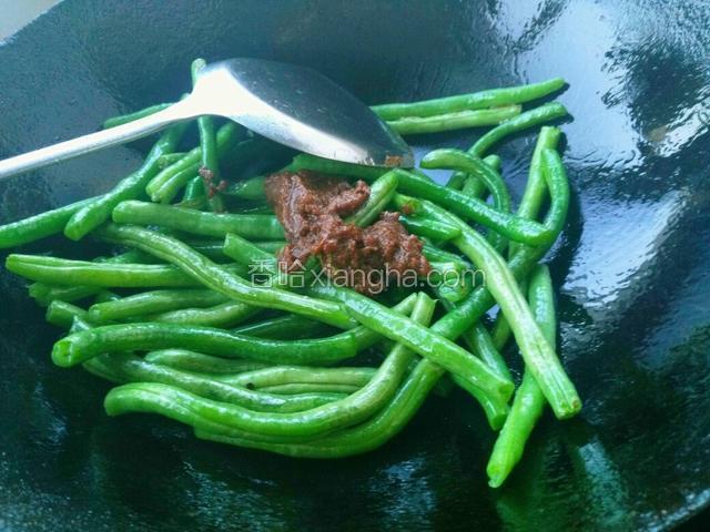 炒到豆角变色发蔫，放入一匙黄豆酱继续翻炒