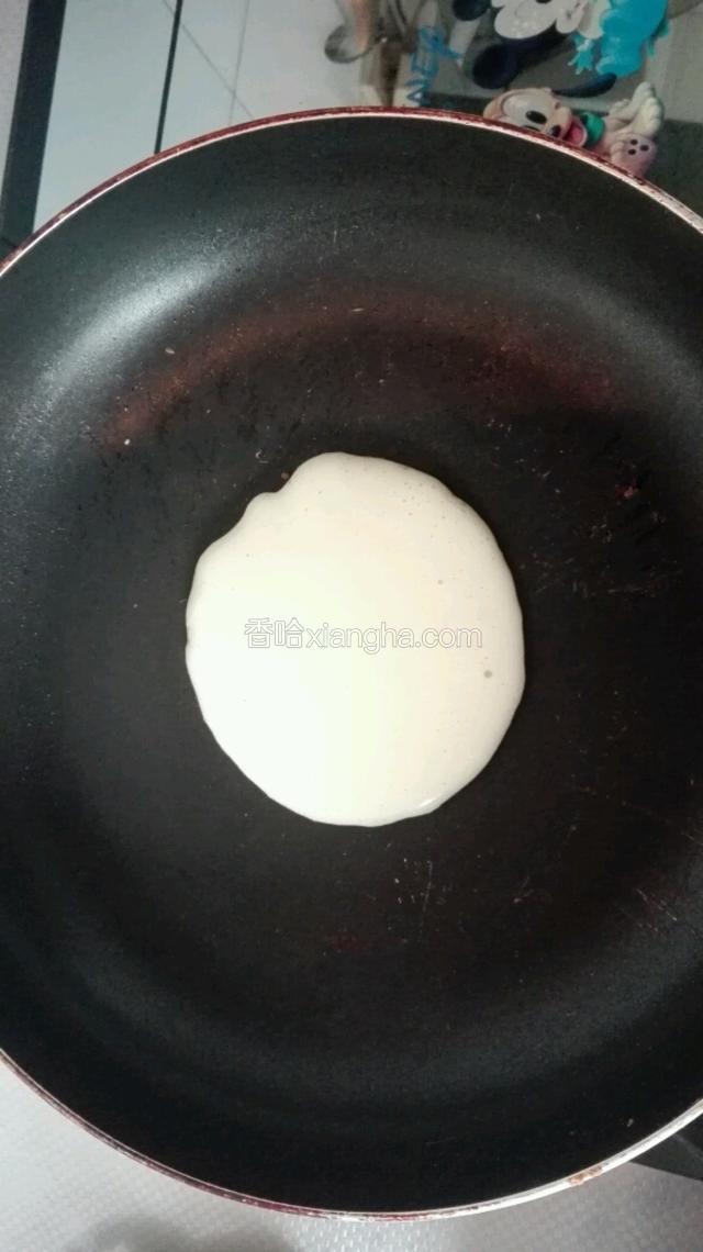 将平底锅大火烧热，不用放油改为小火，用大汤勺盛一勺糊，轻轻地倒入平底锅中，糊会自然化开形成圆形。