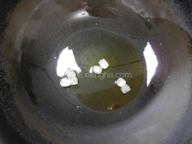 倒上适量的油，放入几粒冰糖，开上小火待融化