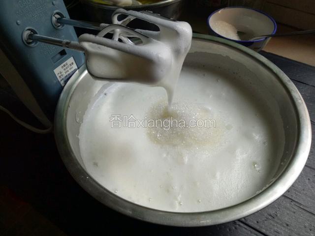 打至提起打蛋器，蛋白挂在打蛋器上不滑落加入剩余白糖的一半继续用电动打蛋器打发。
