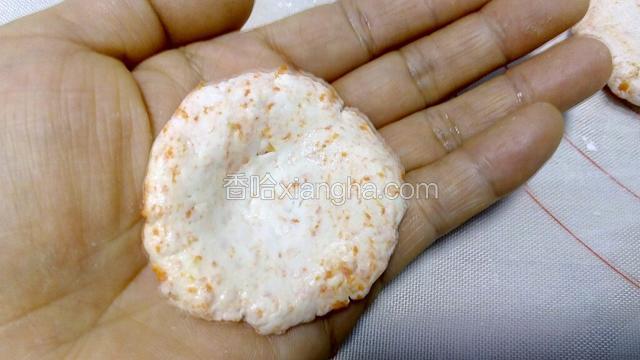 取一个小剂子，用手按压成圆形小饺子皮形状，放于手掌中，并将面皮中间按压出小窝，方便于包馅。