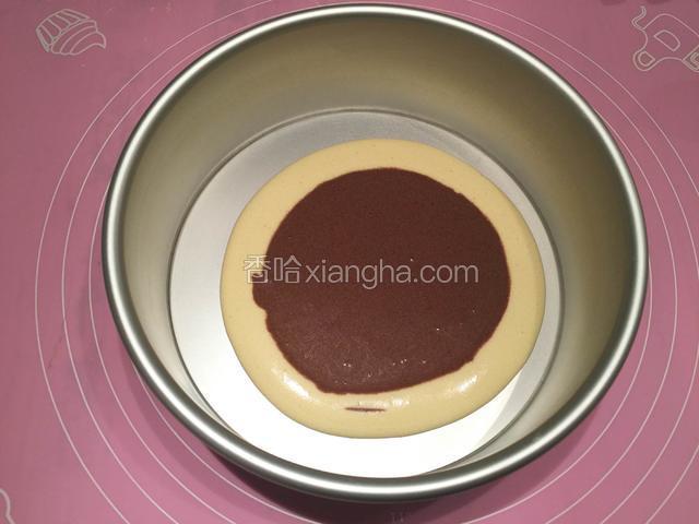 先将一大勺原味面糊倒在蛋糕模具中间，然后在原味面糊中间倒上一大勺可可面糊；（此时可将烤箱预热，设定140度10分钟）