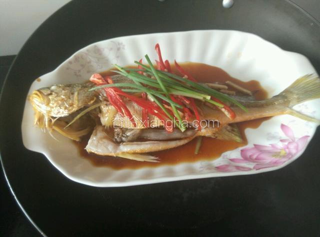 把鱼身上的葱头拣去，铺上红椒丝和葱叶，淋上蒸鱼豉油。