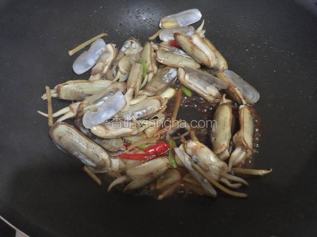 稍微炒几下有的蛏子壳就开了，这时候倒入料酒和生抽翻炒均匀。