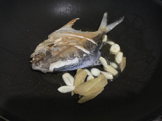 待鱼煎好，放入姜蒜煸香。