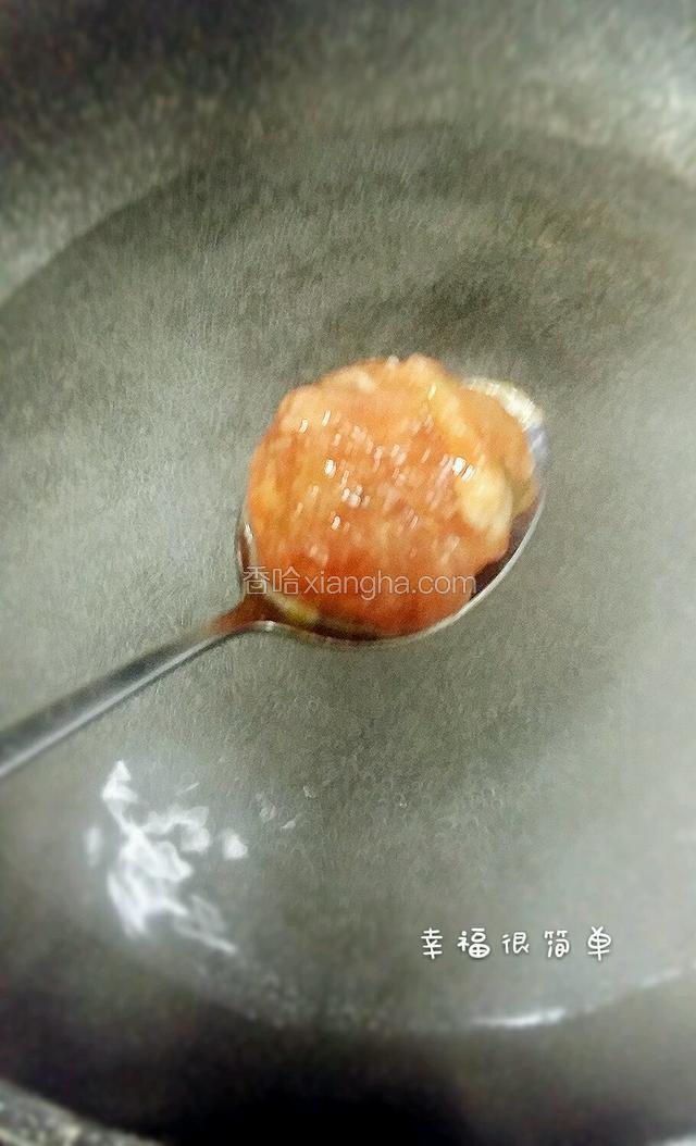 沾了淀粉水的勺子，接住 虎口挤出的肉丸，锅中放入适量的清水，开中小火，下入肉丸。