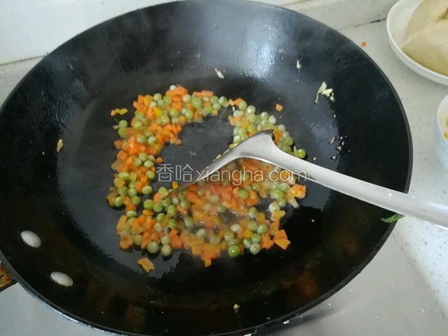 锅里下油倒入红萝卜和豌豆翻炒。