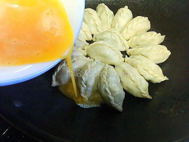 鸡蛋加少许盐打散沿锅边饺子缝隙缓缓倒入使蛋液均匀摊开成圆形。