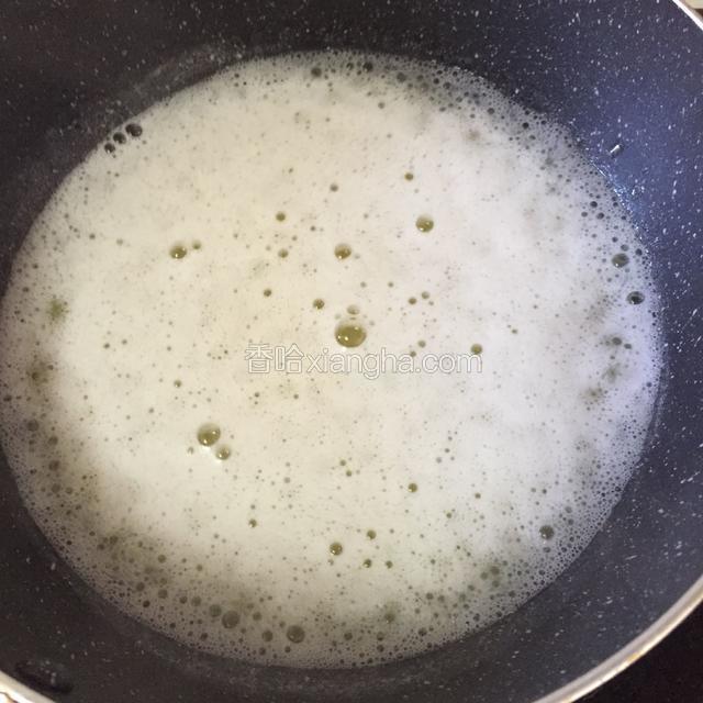 当水烧开冒泡泡转小火倒入面粉，迅速搅拌成团。