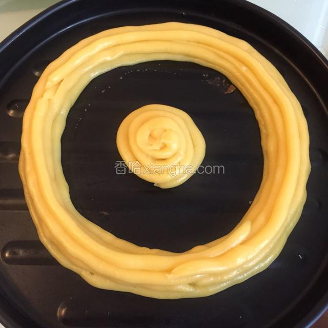 打开迷你烤箱150度预热。把面团倒入裱花袋，尖角处剪一个小口，把面挤到烤盘里。先挤一个圆，并排再来两圈。下层三圈挤好，中间层也来三圈，最上层再来三圈，一层一层摞起来，六寸的大小，直径20cm就可以，在中间的空白处可以挤上圆泡芙。