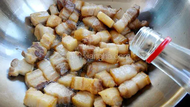 肉块炒出油并有焦黄色时，锅边淋入白酒，盖盖十秒