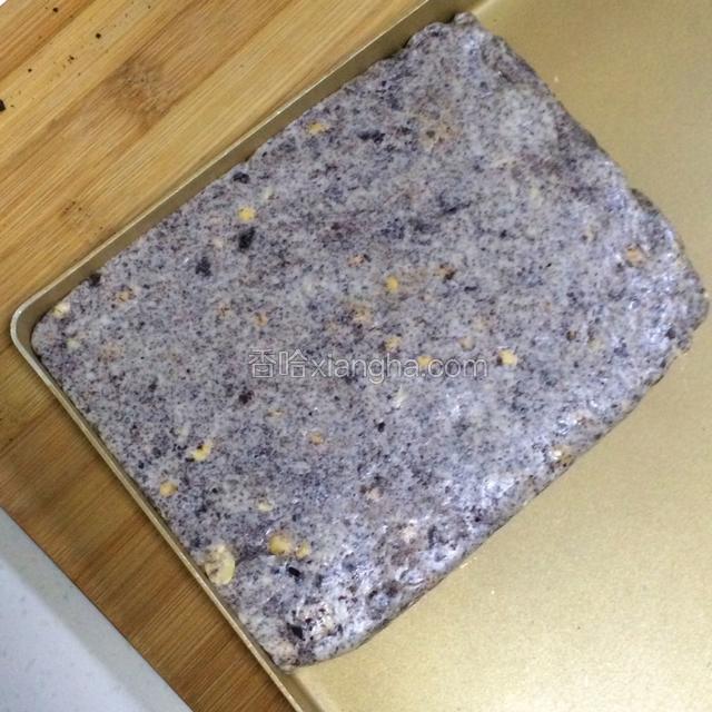 把牛轧糖团倒在不粘烤盘内整形。如果没有不粘盘，可以直接放在油纸上整形的，有擀面杖的话可以直接擀平，边角可以借用刮板整平。