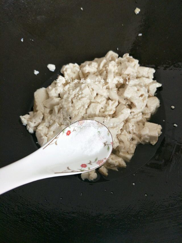 用锅铲把豆腐弄碎了，加入盐一勺。