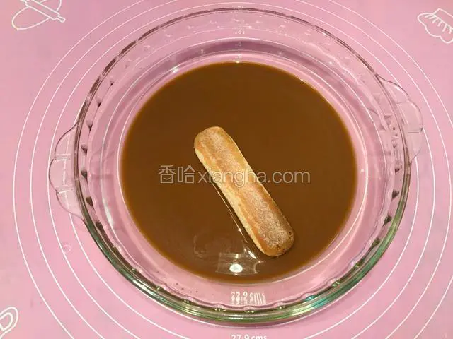 取一片手指饼干，在咖啡酒混合液里快速蘸一下，让手指饼干蘸满咖啡酒混合液；