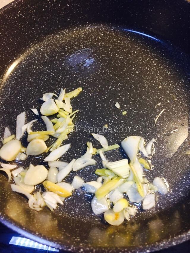 重新起锅，倒入适量玉米油，油温升高后先把蒜片煸香，再倒入葱姜煸炒