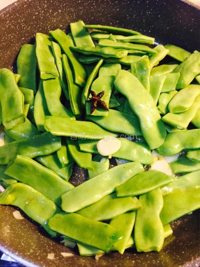 等葱姜蒜都煸出香味后，加大料瓣和扁豆下锅炒热
