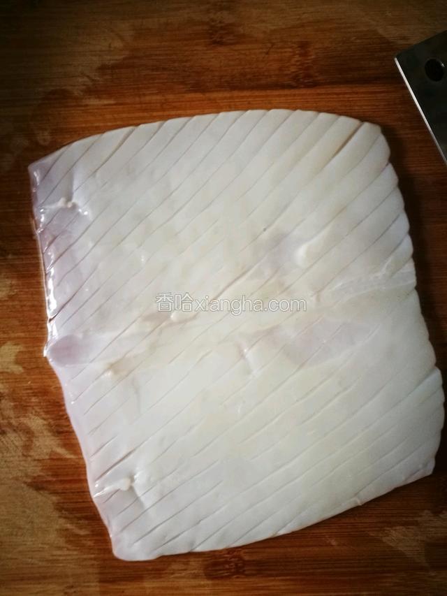 然后用刀尖儿在鱿鱼内面，45度斜划鱿鱼，注意不要划透