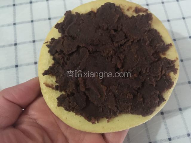 取一个饼背面朝上，抹上适量的豆沙。