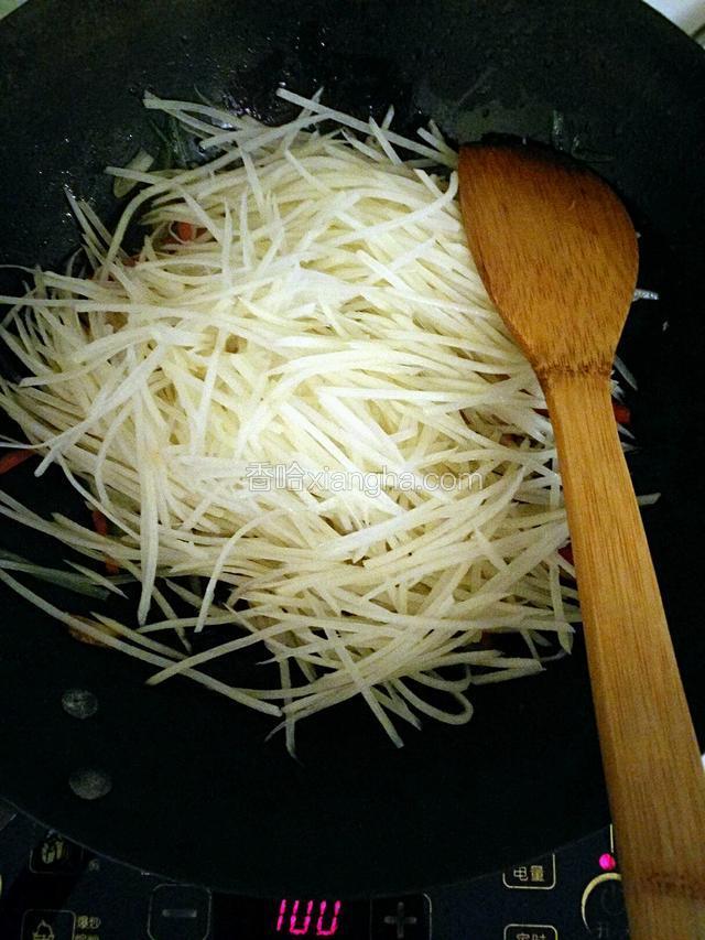 从水中捞出土豆丝放入锅中。倒适量白醋。翻炒均匀。